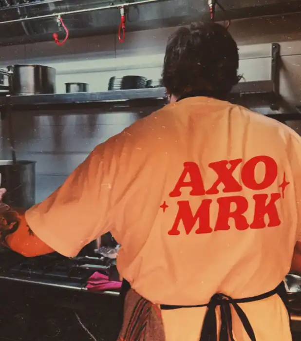 Camiseta con el lema «AXO MRK» en la cocina