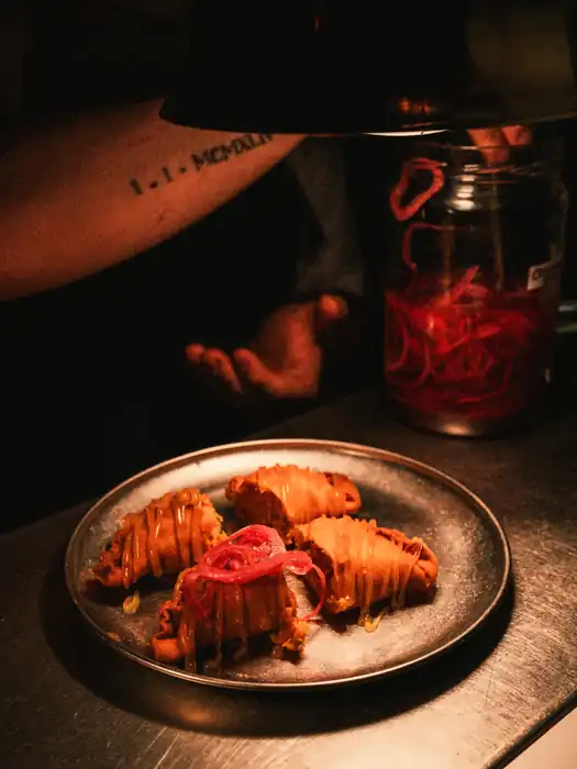 Empanadillas con cebolla roja encurtida en plato de metal