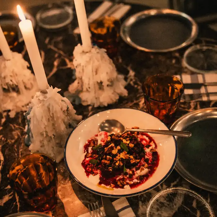 Remolacha con burrata en plato de borde azul, entre velas