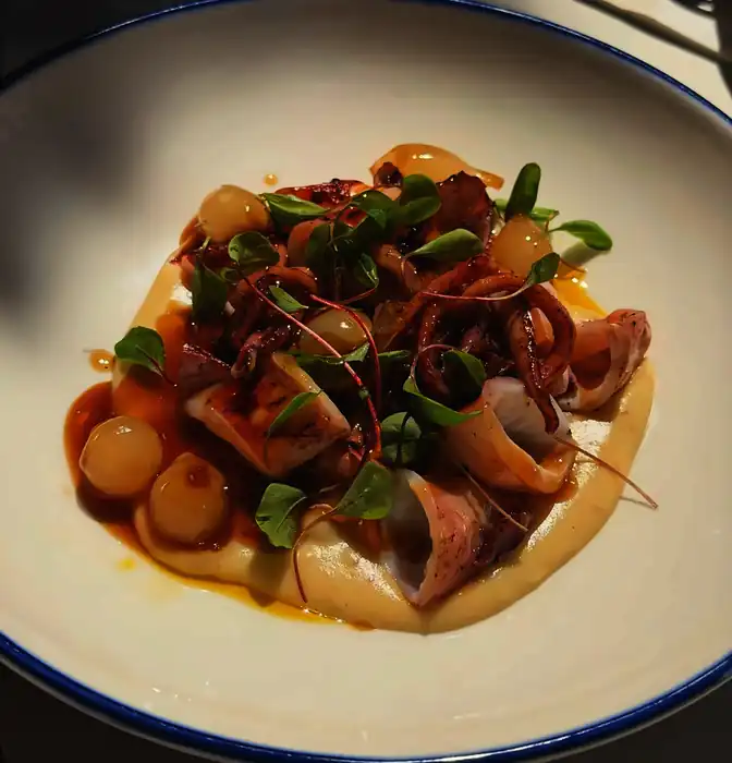 Txipirón de anzuelo con jugo de cebolla en plato de borde azul